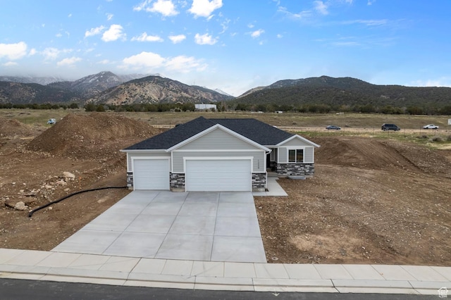 view of front facade with a mountain view, a garage, stone siding, and concrete driveway