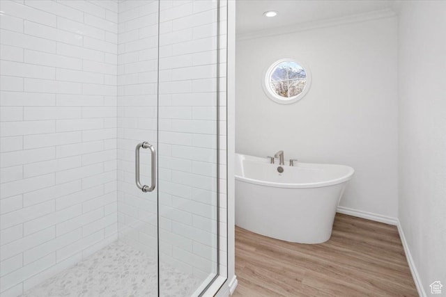bathroom featuring crown molding, a shower stall, baseboards, wood finished floors, and a freestanding bath