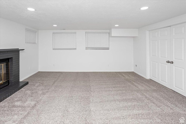 unfurnished living room featuring a brick fireplace, carpet, baseboards, and a textured ceiling