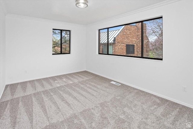 carpeted spare room with ornamental molding, visible vents, and plenty of natural light