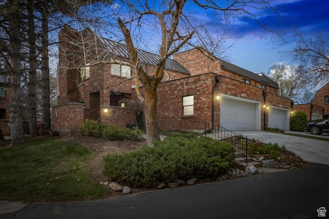 view of front of property with driveway, an attached garage, and brick siding
