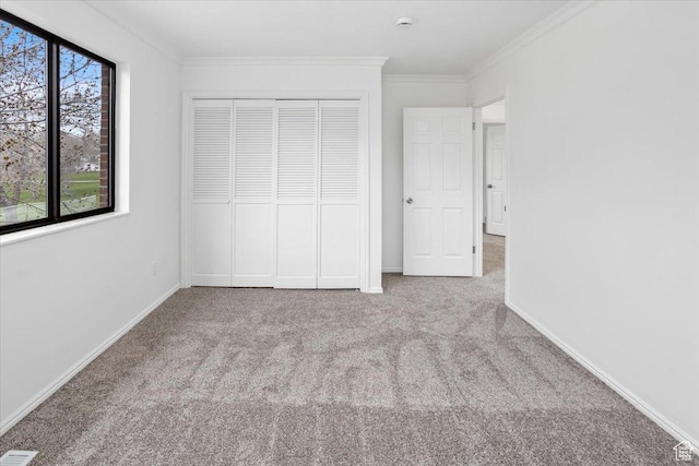 unfurnished bedroom featuring baseboards, carpet floors, ornamental molding, and a closet