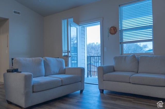living area featuring visible vents, vaulted ceiling, and wood finished floors