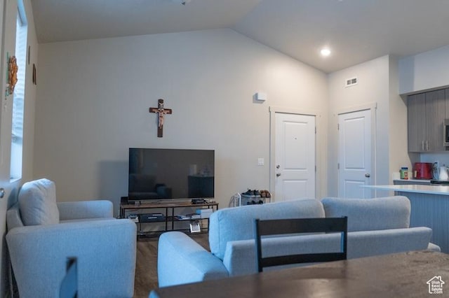living room featuring lofted ceiling, visible vents, and wood finished floors