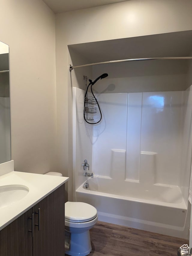 bathroom featuring toilet, vanity, shower / bath combination, and wood finished floors