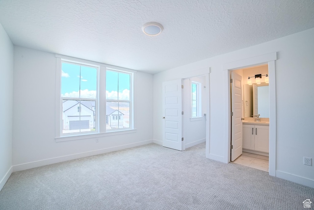 1258 S Boxelder Dr, Saratoga Springs, UT 84005 - unfurnished bedroom with light carpet, baseboards, a textured ceiling, a sink, and ensuite bathroom