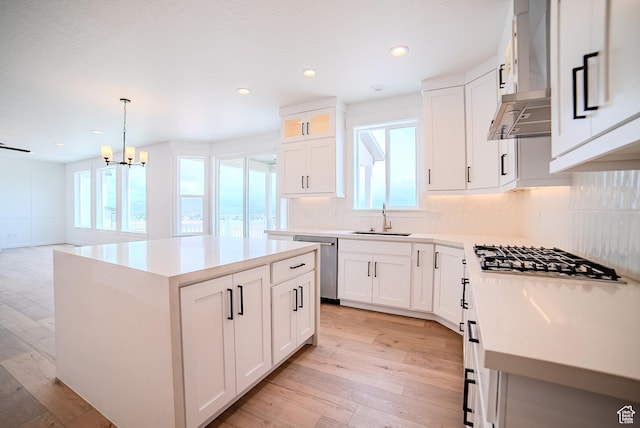 1258 S Boxelder Dr, Saratoga Springs, UT 84005 - kitchen featuring stainless steel appliances, a sink, wall chimney exhaust hood, a center island, and light wood-style flooring