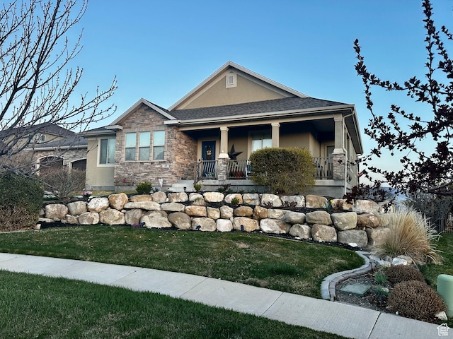 view of front facade featuring stucco siding, a front lawn, and covered porch