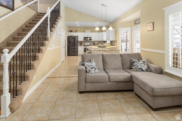 living room featuring light tile patterned floors, stairway, and a notable chandelier