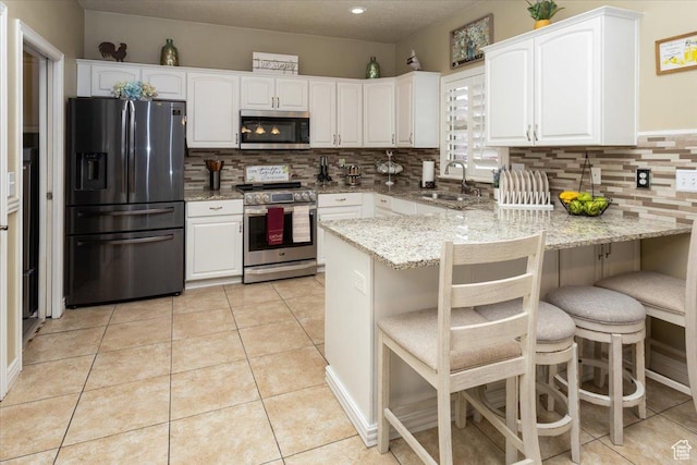kitchen featuring white cabinetry, a sink, light tile patterned floors, and appliances with stainless steel finishes