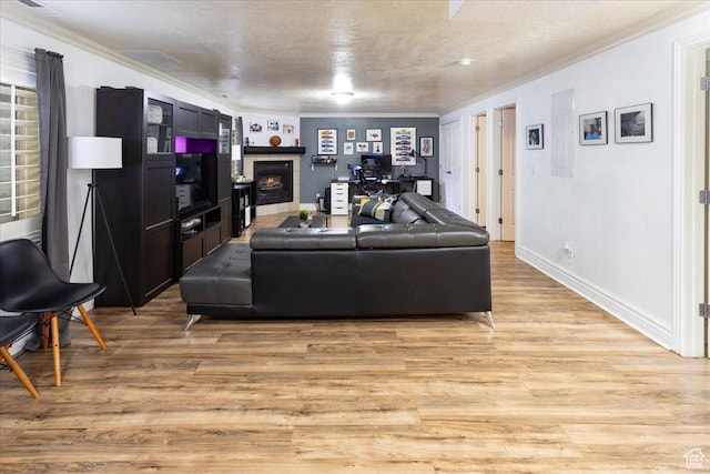 living area featuring a tile fireplace, crown molding, a textured ceiling, and light wood-type flooring