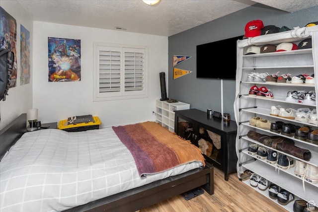 bedroom with a textured ceiling, visible vents, and light wood-style floors