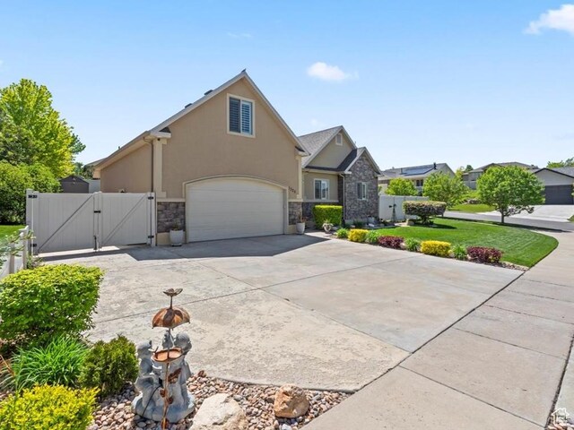 1325 W Trailside Dr, Santaquin, UT 84655 - view of front facade with a gate, stone siding, stucco siding, driveway, and a garage
