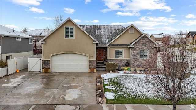 view of front facade with stone siding, a garage, stucco siding, and fence
