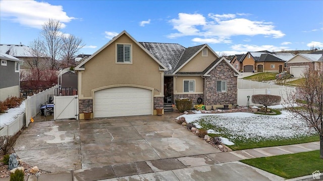 view of front of home with a gate, stone siding, concrete driveway, stucco siding, and fence