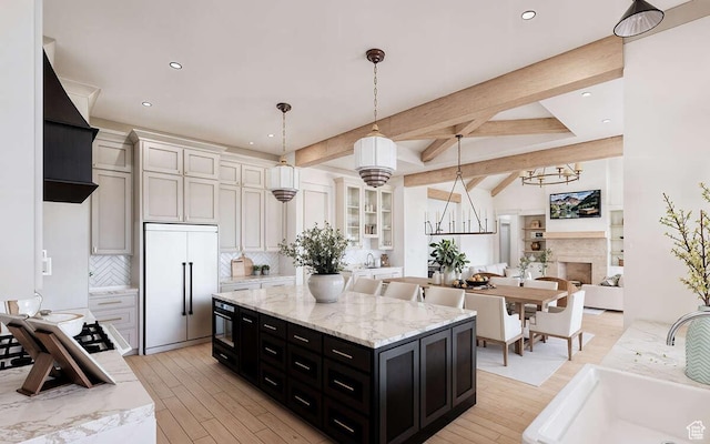 kitchen with open floor plan, dark cabinetry, a chandelier, a sink, and built in fridge