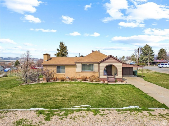 view of front of property with driveway, a front yard, brick siding, an attached carport, and a chimney