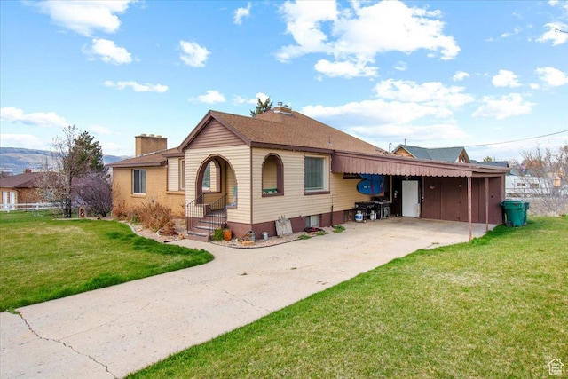 bungalow with a chimney, an attached carport, a front lawn, driveway, and a shingled roof