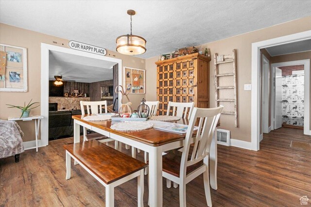 dining room with wood finished floors, a textured ceiling, baseboards, and visible vents
