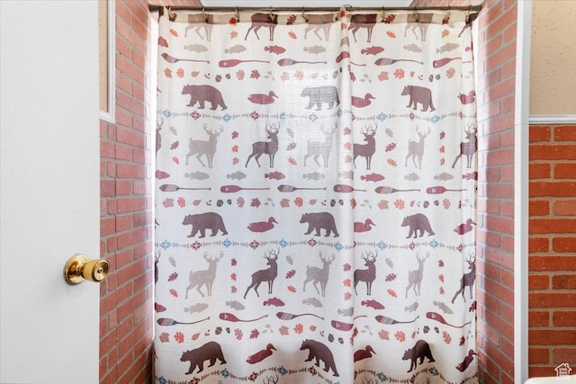 bathroom with a shower with curtain and brick wall