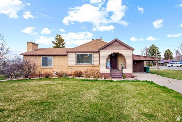 view of front of house with concrete driveway, a chimney, brick siding, a front lawn, and a carport