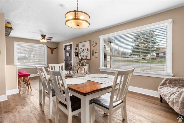 dining room featuring baseboards, wood finished floors, and ceiling fan with notable chandelier