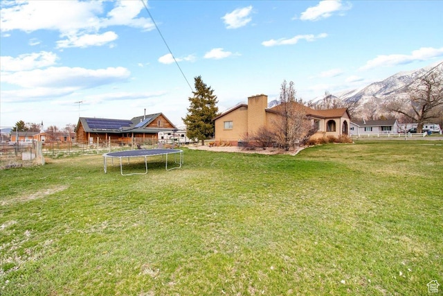 view of yard with fence, a mountain view, and a trampoline