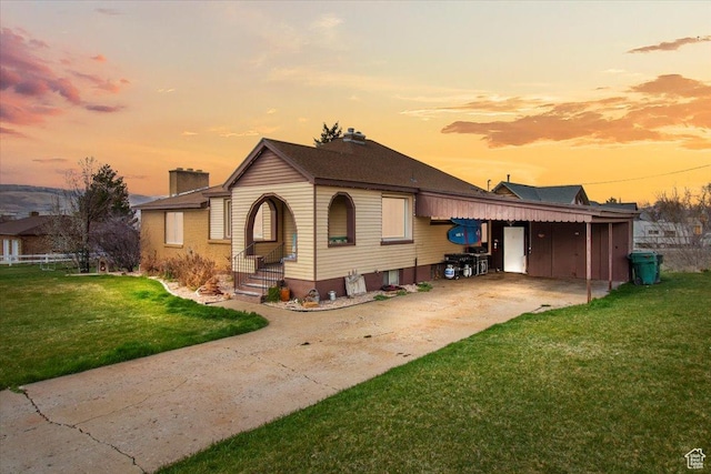 view of front facade with an attached carport, a front yard, and a chimney