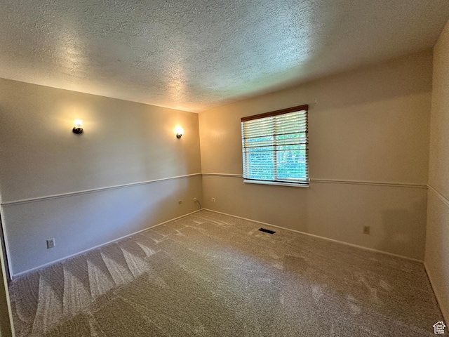 carpeted empty room with a textured ceiling and baseboards