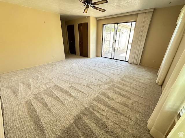 spare room with ceiling fan, a textured ceiling, and carpet floors