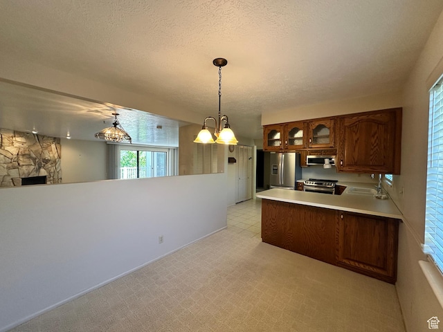 kitchen featuring stainless steel appliances, a peninsula, a sink, glass insert cabinets, and light countertops