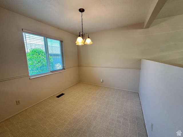 carpeted spare room with a chandelier