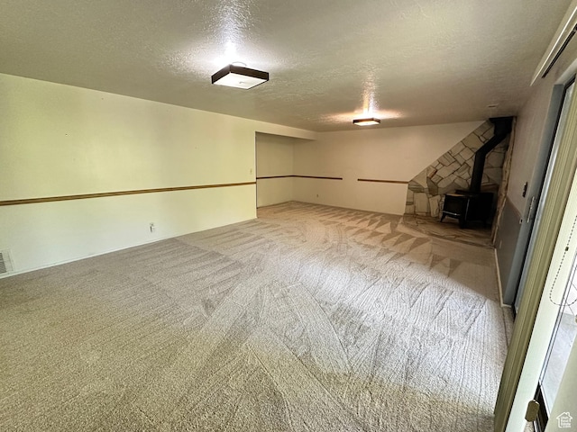 finished below grade area with a textured ceiling, a wood stove, and carpet