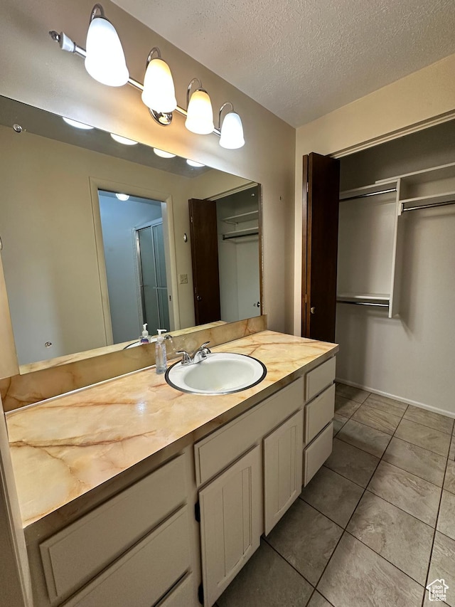bathroom featuring a textured ceiling, vanity, and tile patterned flooring
