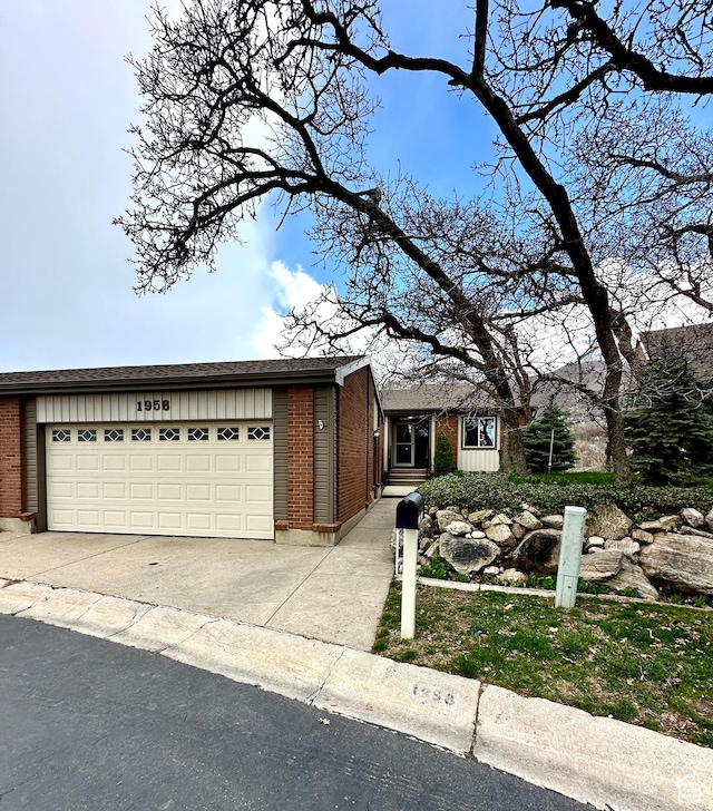 view of front of house featuring board and batten siding, brick siding, driveway, and a garage