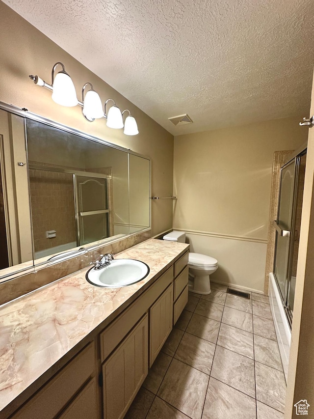full bathroom featuring a textured ceiling, vanity, toilet, and bath / shower combo with glass door