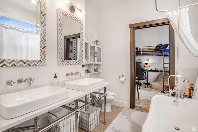 bathroom featuring a sink, baseboards, a freestanding tub, and toilet