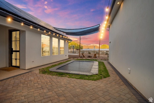 pool at dusk with a patio