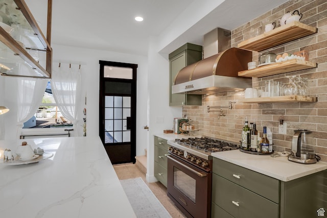 kitchen featuring green cabinets, backsplash, high end stainless steel range, and wall chimney exhaust hood