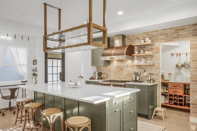 kitchen featuring wall chimney exhaust hood, stainless steel gas stovetop, a center island, light countertops, and backsplash