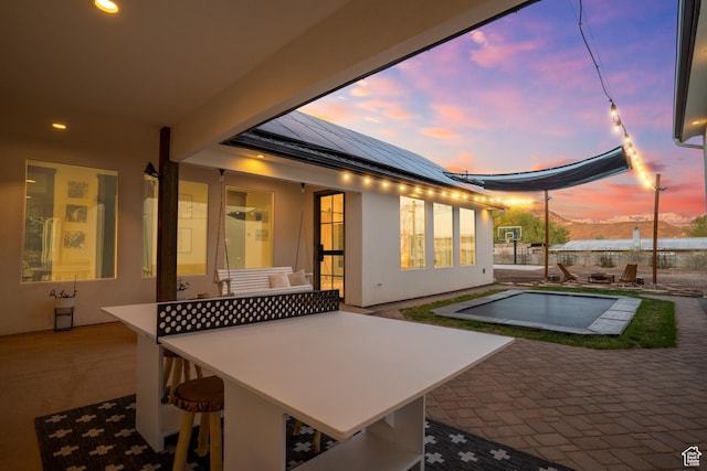 pool at dusk featuring an outdoor pool and a patio area