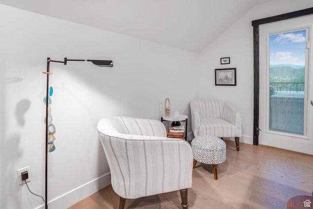 living area featuring wood finished floors, baseboards, and vaulted ceiling