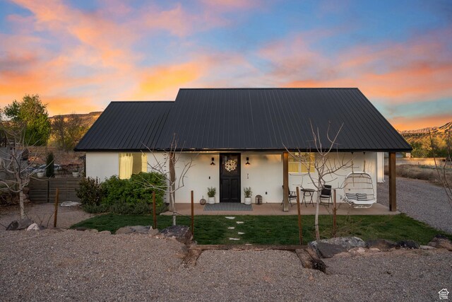 view of front of house with a patio, metal roof, and stucco siding