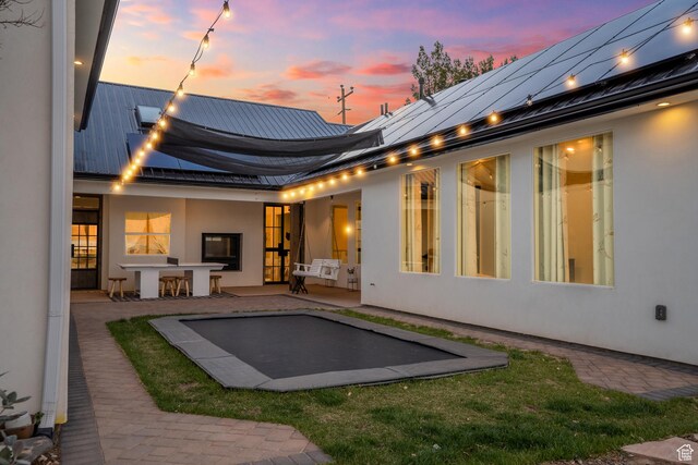 back of property at dusk featuring a standing seam roof, a patio, metal roof, and stucco siding