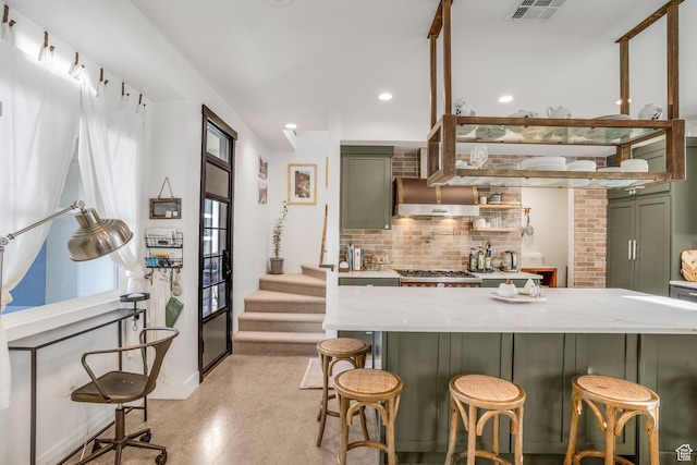 kitchen featuring light stone countertops, green cabinets, visible vents, and backsplash