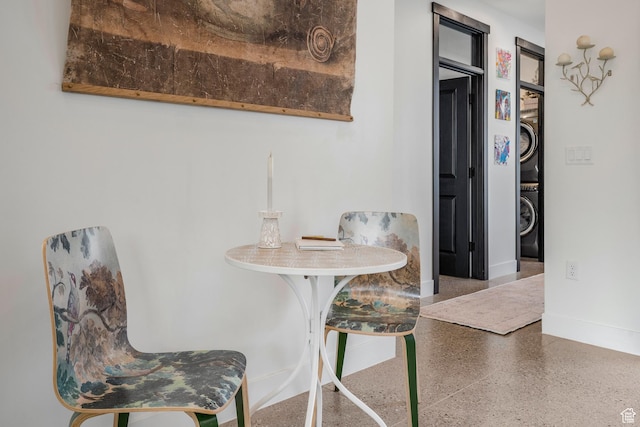 dining room with stacked washer and dryer, speckled floor, and baseboards