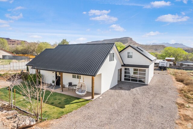 rear view of property with a patio area, a mountain view, metal roof, and stucco siding