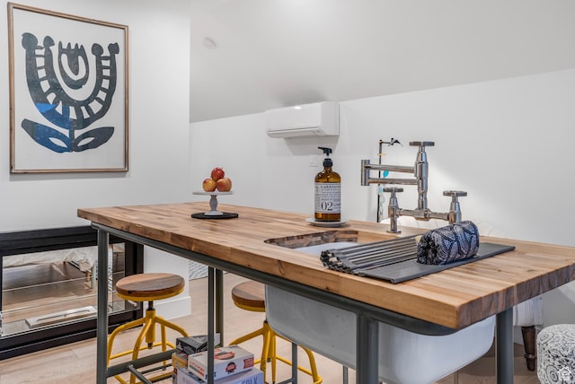 kitchen with butcher block counters, a wall unit AC, and wood finished floors
