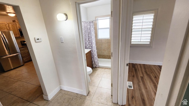 hall with light tile patterned flooring, baseboards, and visible vents