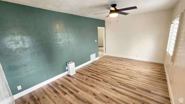 unfurnished room featuring a ceiling fan, a textured ceiling, baseboards, and wood finished floors
